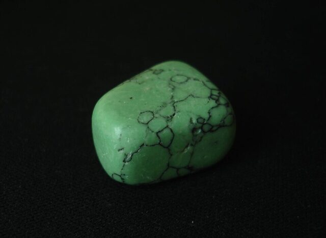 Polished pale green chrysoprase gemstone with dark mineral veins