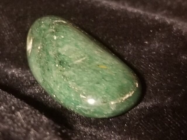 Natural green aventurine gemstone specimen on black background, green aventurine meaning and properties