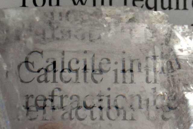 Transparent Iceland spar calcite crystal showing double refraction of printed text