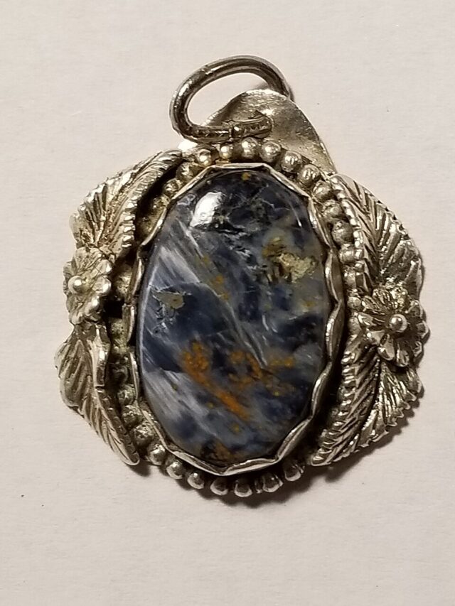 Pietersite gemstone with fibrous blue and golden chatoyant patterns set in a silver pendant
