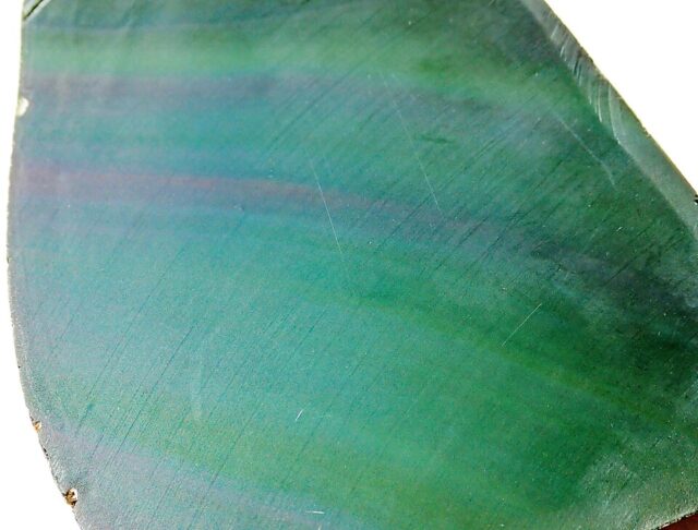 Cut rainbow obsidian volcanic glass stone showing multicolored iridescent bands