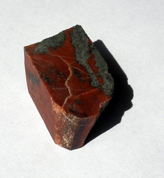 Natural red jasper stone with a cut surface showing its deep red opaque color
