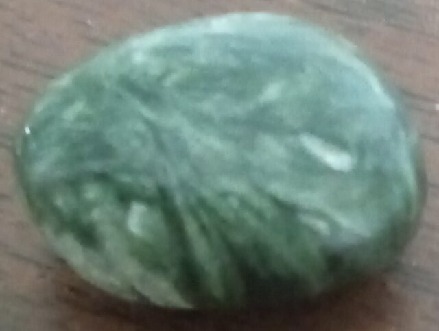 Natural green seraphinite gemstone showing feathery silvery mineral patterns